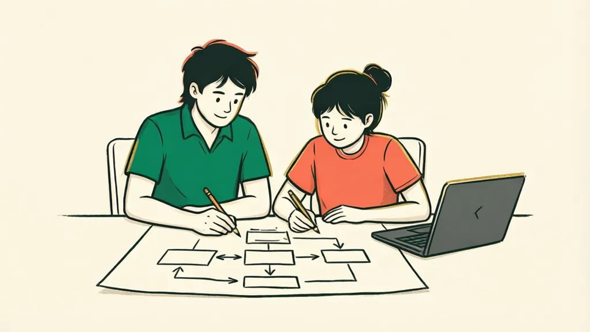 A volunteer and a teenager sketching a branching flowchart on paper beside a closed laptop